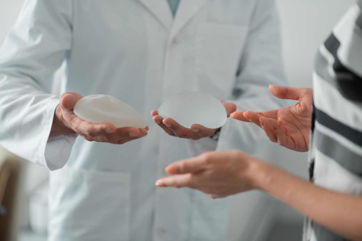 Plastic surgeon answering breast augmentation questions holding breast implants