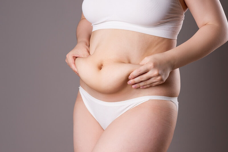 A woman wearing a white bikini top and matching underwear, posing confidently against a neutral background.
