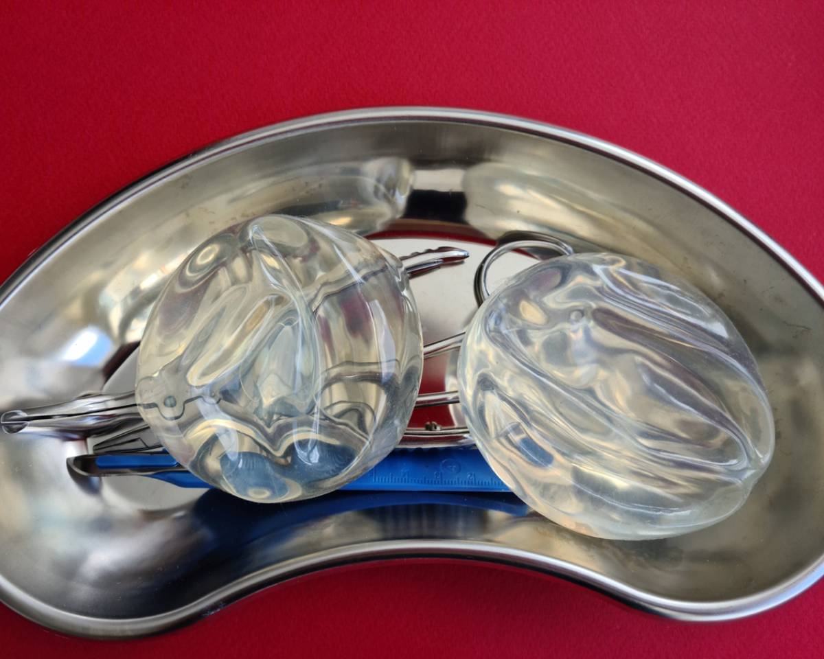 Two glass balls resting in a metal bowl, placed on a vibrant red surface, creating a striking visual contrast.