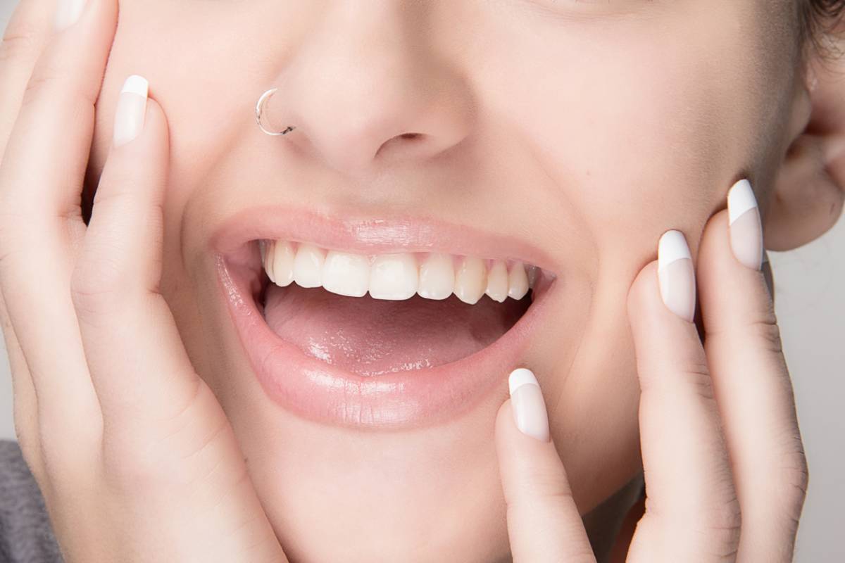 A woman showcasing her bright white teeth and wearing a stylish nose ring, exuding confidence and charm.