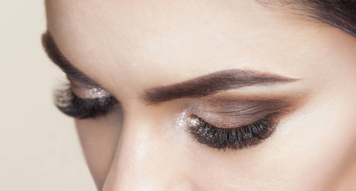A woman with long eyelashes and dark makeup, exuding elegance and confidence in her striking appearance.