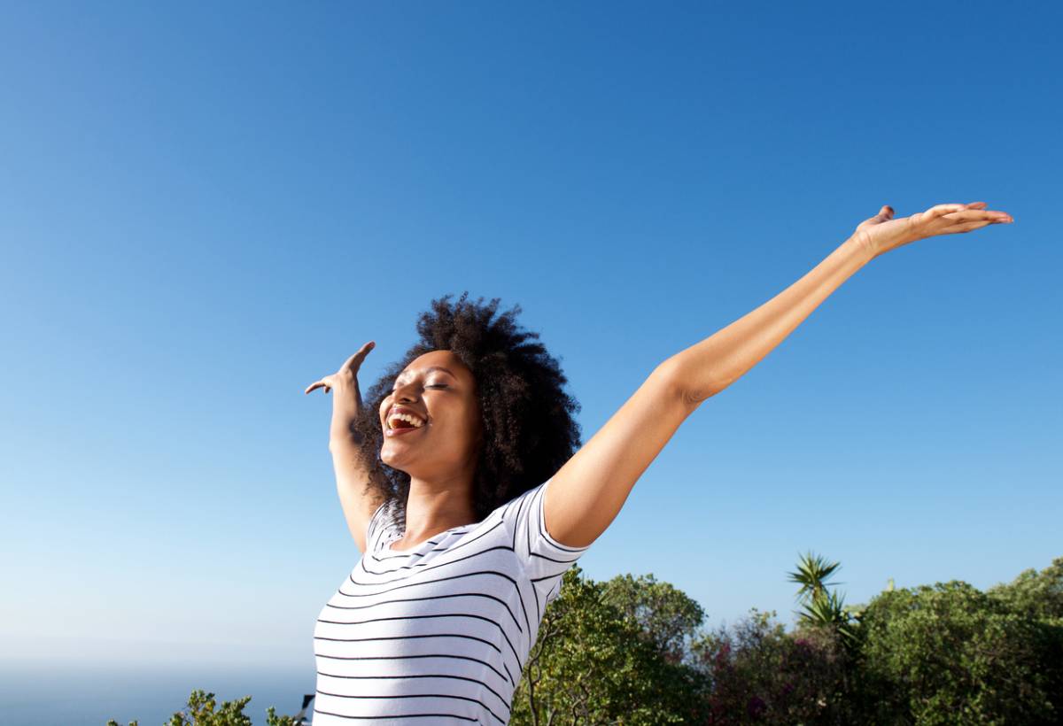 A woman joyfully extends her arms upward, embracing the moment with a sense of freedom and exhilaration.