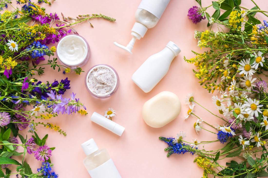 A collection of beauty products displayed on a soft pink background, showcasing vibrant colors and elegant packaging.