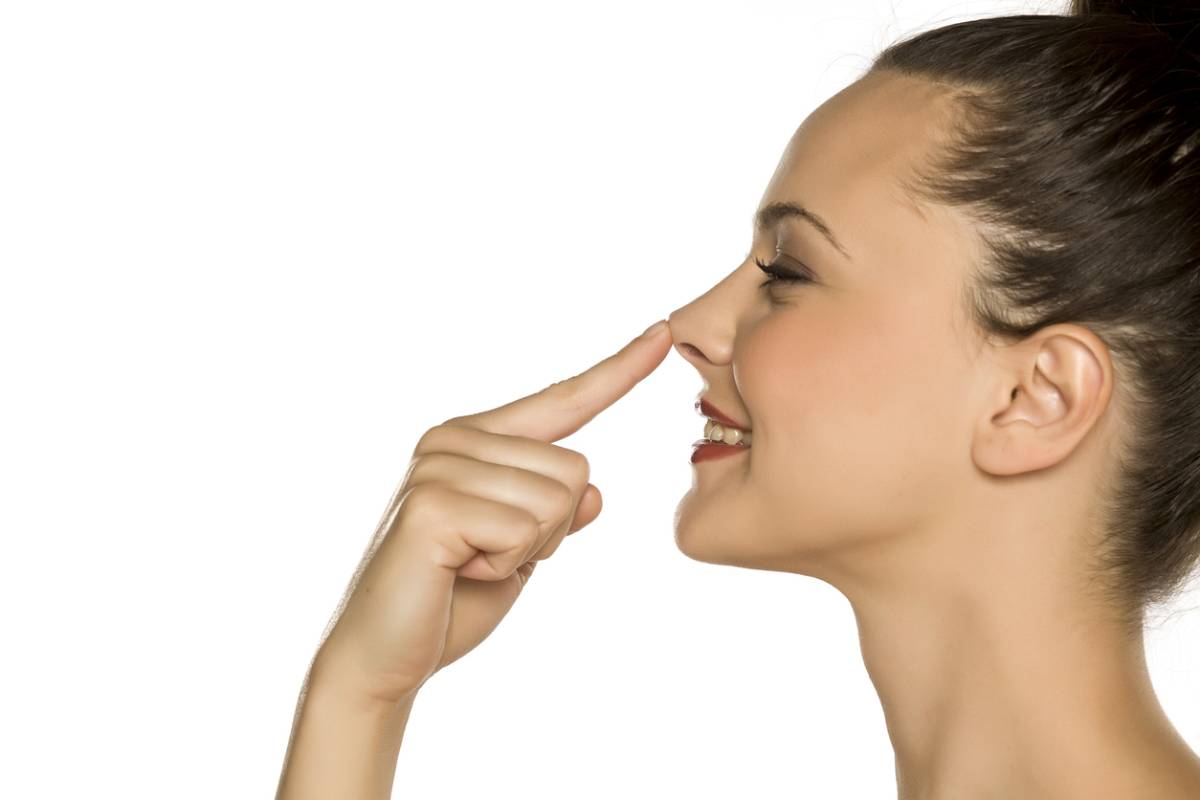 A woman gently touches her nose with her finger, showcasing a moment of contemplation or curiosity.